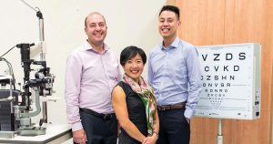 Photograph of the Clinical Trials Research Centre team standing face to camera, smiling, in a consultation room.