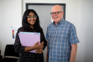 A clinical trial coordinator standing next to a participant.